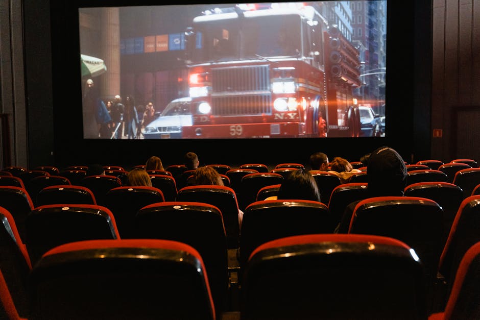People seated in a cinema watching a movie on a large screen.